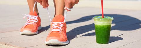 woman tying her shoes next to a green smoothie